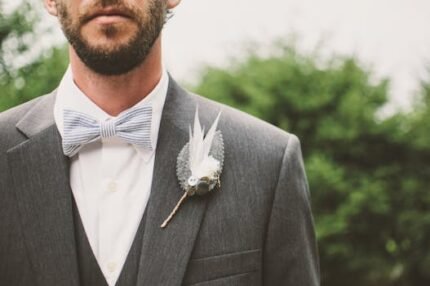 Close-up of a groom in a formal suit with bow tie and boutonniere. Elegant style.